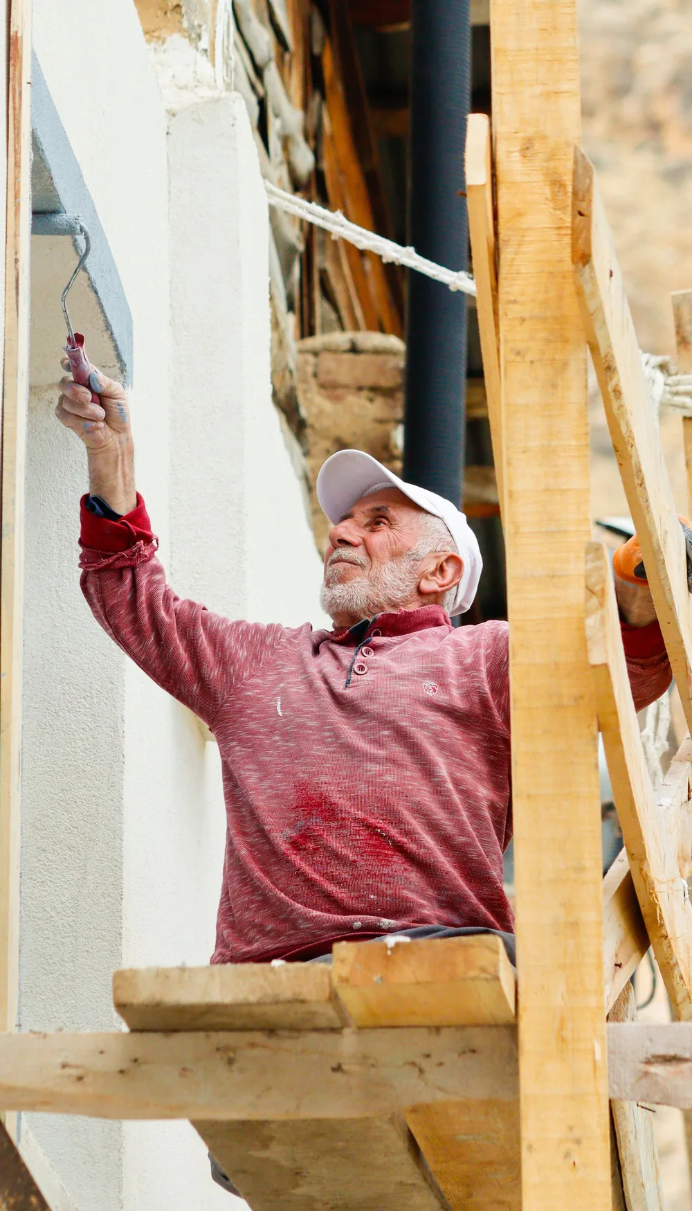 Painter decorating an exterior wall from scaffolding